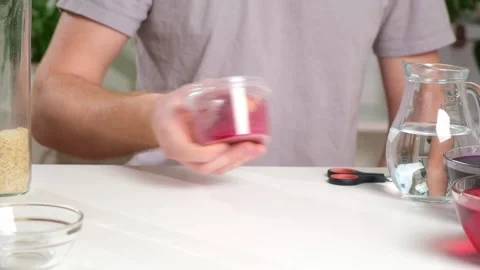 Man lays an egg and shakes container rice color egg. unusual way coloring and Stock Footage 238501255