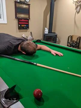 A man lays face down on a pool table Stock Photos