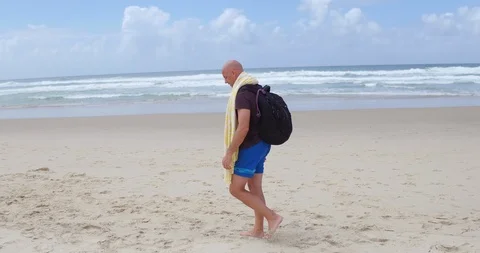 Man lays his towel down and finds his place at the beach Stock Footage 87984239