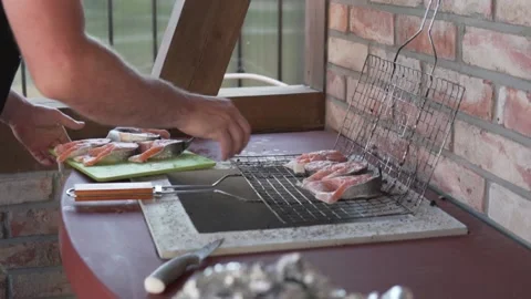 A man lays out a red fish on a grill for grilling in the summer in a street Stock Footage 158040790