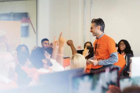 Man leading cheering hackers coding for charity at hackathon Stock Photos