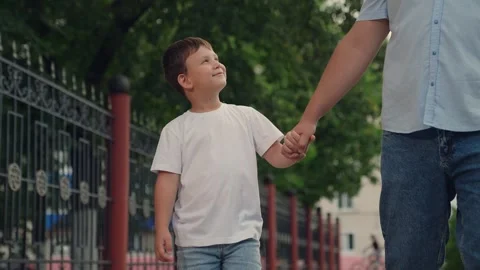 Man leads son by the hand boy, little happy boy holds father hand in park Stock Footage 302473380