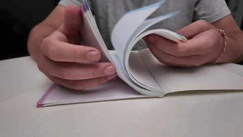 A man leafing through the blank pages of a notebook with his finger Stock Footage 318344884