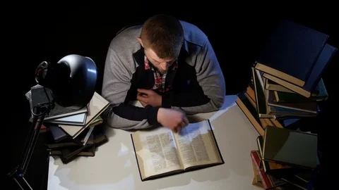 Man leafing through the book and falls asleep. Black background. View from above Stock Footage