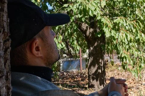 The man leaned against the trunk of a walnut tree. Foto stock