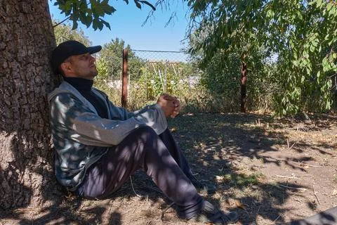 The man leaned against the trunk of a walnut tree. Stock Photos