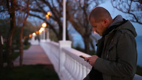 The man leaned on the balustrade with a cigarette and a smartphone in his hands. Stock Footage 150227321