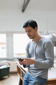 Man leaning against a pool table using a mobile phone Stock Photos