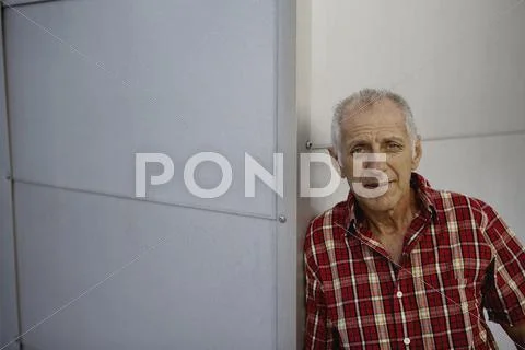 Man leaning against wall, looking at camera Stock Photos