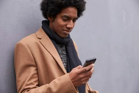 Man Leaning Against Wall Using Mobile Phone On City Street Stock Photos