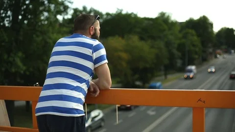 Man leaning on the balcony and looking on highway Stock Footage 76978522