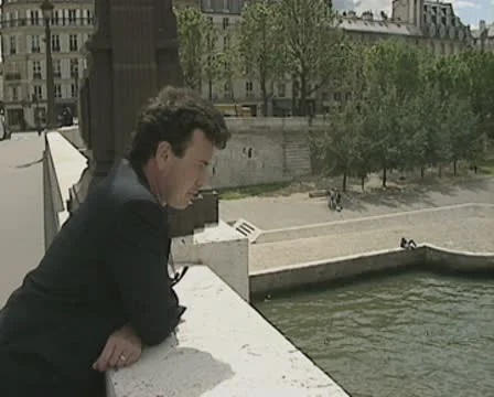 Man leaning on bridge looking at Notre Dame cathedral Stock Footage 8919466