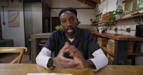 Man leaning forward, gesturing while explaining ideas in kitchen at table with Video stock 344536670