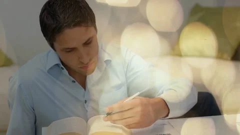 Man leaning forward, scribbling with pen, flipping pages studying open book with Stock Footage 333911294