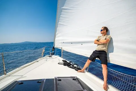 Man leaning on full sails of a sailing yacht in the open sea near Croatia Stock Photos