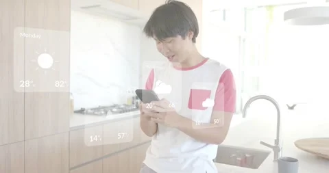Man leaning in kitchen, holding smartphone tapping scrolling showing weekly AR Stock Footage 316964058
