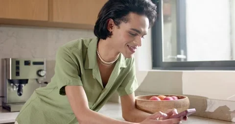 Man leaning on marble countertop in kitchen reading smartphone message, smiling Stock Footage 344330899