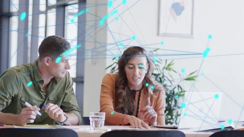 Man leaning, pointing doc, starting teal node overlay over desk, woman following 動画素材 333369028