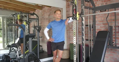 Man leaning on squat rack at gym, shifting weight, glancing mirror, checking Stock Footage 337541657