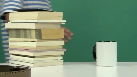 Man Leaning on Stack of Books with White Cup on Table Green Screen Background Video stock 344678267