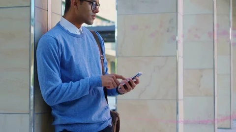 Man leaning on tiled column, tapping phone, initiating animated tech chart Stock Footage 333234416