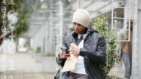 Man leaning on wall scrolling phone eating and tapping making binary icons Video stock 332613986