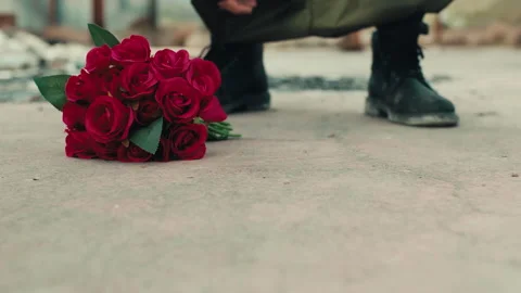 Man leans bunch of red flowers on the ground Stock Footage 192858724