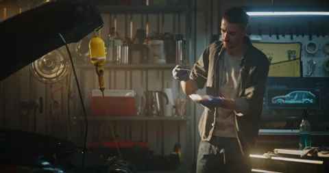 Man Leans Over Open Engine Bay and Pulls Out Oil Dipstick Check Level Stock Footage 329387909