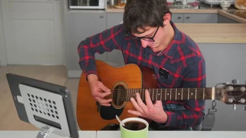 Man learning guitar at home using tablet tutorial, cozy setup Vídeo Stock 315066824