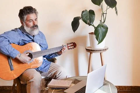 Man learning guitar at home using an online lesson Foto stock