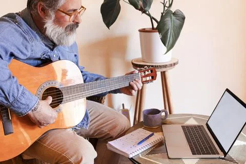 Man learning guitar at home with virtual lesson Stock Photos