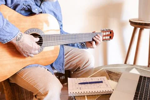 Man learning guitar at home with virtual lesson Stock Photos