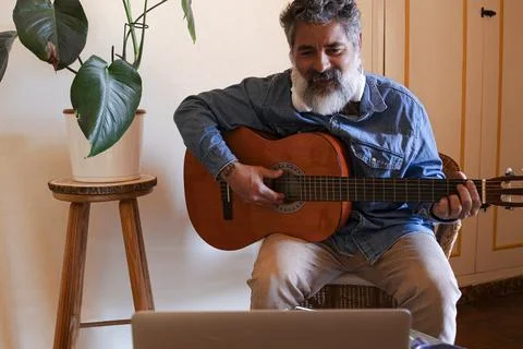 Man learning guitar online using laptop at home Stock Photos
