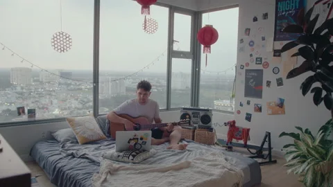 Man Learning Guitar with Video Lessons on Laptop in Bedroom Stock Footage 236686709