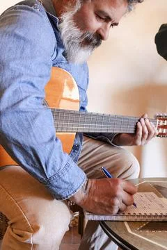 Man learning guitar, writing music notes for online lesson Stock Photos