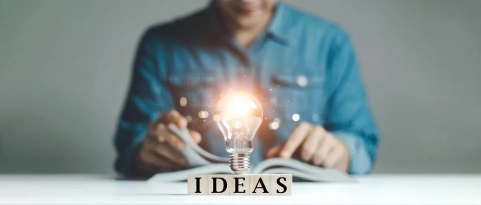 Man learning or reading book with lightbulb, wood block with Word Ideas, conc Foto stock