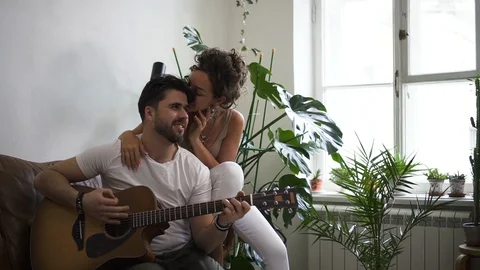 Man learning to play guitar and his wife or girlfriend listening Spbd. male and Stock Footage 128286436