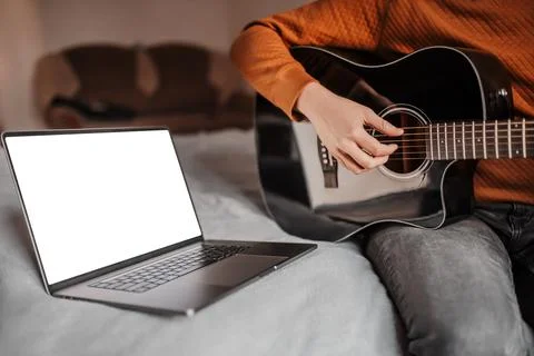 Man learning to play guitar with the help of online learning at home. Guy sit Stock Photos
