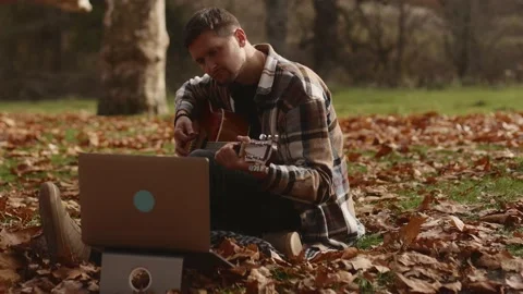 Man learning to play guitar in an online music class with a laptop Stock Footage 233330593