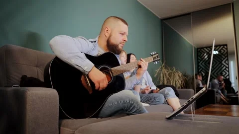 A man is learning to play the guitar remotely and learns new chords Stock Footage 265104832