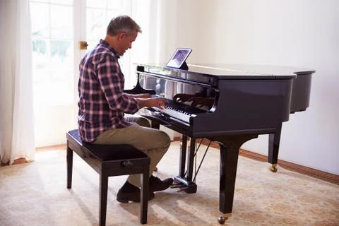Man Learning To Play Piano Using Digital Tablet Application Stock Photos