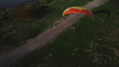 A man learns to control a paraglider from the ground, a cyclist passes by Stock Footage 252174010