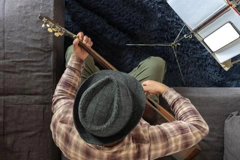 A man learns to play the guitar with the help of his cell phone Stock Photos