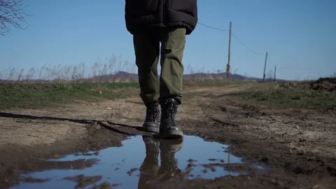 A man in leather boots walks on a puddle Stock Footage 126358867