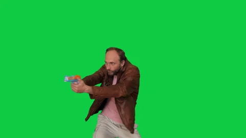 Man in Leather Jacket Aims Toy Gun at Imaginary Enemies on Green Screen Stock Footage 287123839