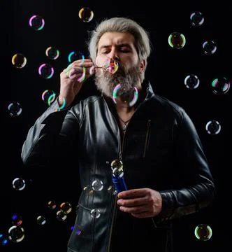 Man in leather jacket blowing Soap bubbles. Happiness. Good mood. Childhood c Stock Photos