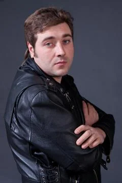 Man in a leather jacket on a gray background Stock Photos
