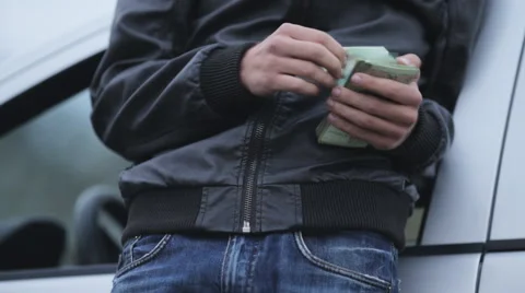 A man in a leather jacket near the machine counts the money Stock Footage 55335001