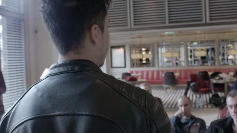 Man in Leather Jacket Speaking to Group in Lounge Stock Footage 343970810