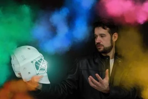 A man in a leather jacket is standing in the middle colored smoke and holding Stock Photos